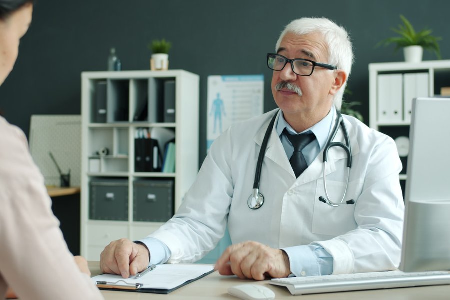 Physician consulting with a patient at a desk.