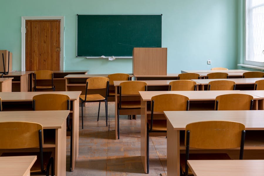 Sunlit empty classroom with wooden desks.
