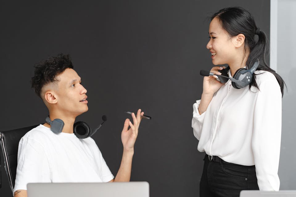 Two colleagues wearing headsets in conversation.